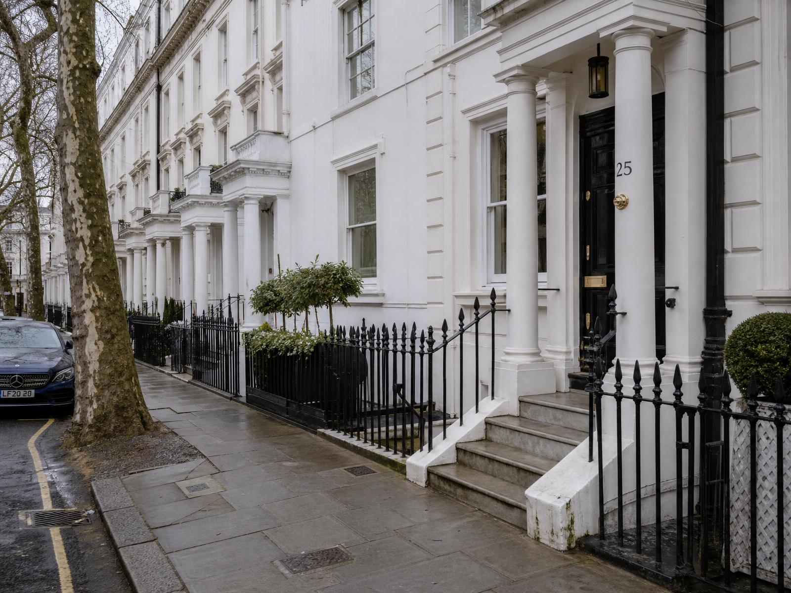 A quiet residential street of white stucco terraced houses in Prime Central London